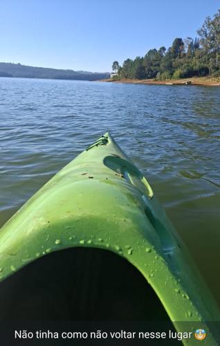 a view of the end of a green kayak in the water at Chácara com acesso à represa in Ibiúna