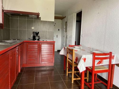 une cuisine avec des placards rouges et une table avec des chaises dans l'établissement Studio 5 Pers. à 100m des Pistes, Balcon N/O, Proche Commerces - Risoul 1850 - FR-1-330-570, à Risoul