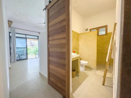 a pivot door in a bathroom with a toilet at The Coco Paradise in Jambiani