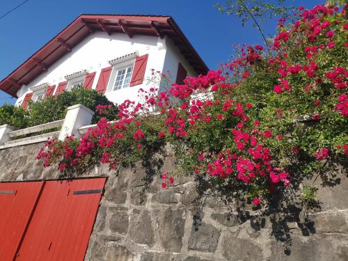 a house with pink flowers on a stone wall at Chambres d'hôtes "HOR DAGO" près de la gare d'Hendaye avec le petit-déjeuner in Hendaye