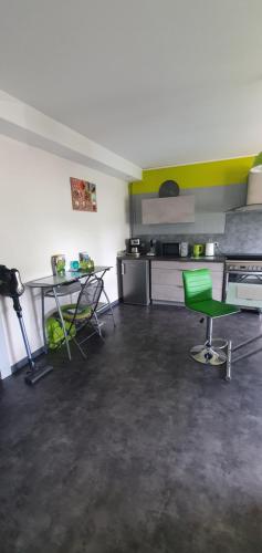une chambre avec une chaise verte et une cuisine dans l'établissement Appartement idéal au calme !, à Hadol
