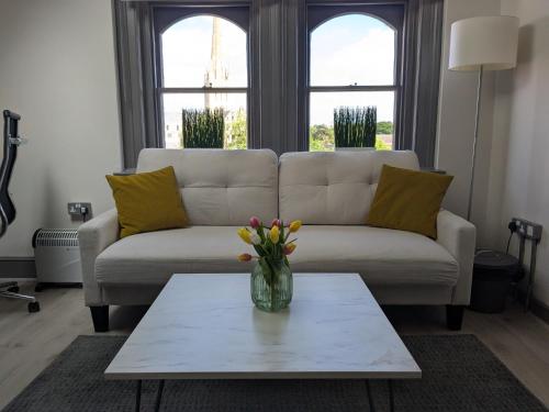 a living room with a couch and a vase of flowers on a table at Digital Nomad Studio in Norwich