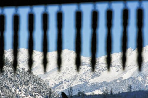 a view of a snow covered mountain through a fence at Shivadya - A Luxury Boutique Experience in Manāli