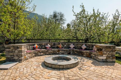 a stone patio with a fire pit in a yard at Shivadya - A Luxury Boutique Experience in Manāli