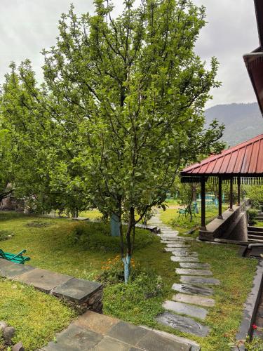 a tree on a stone path next to a building at Shivadya - A Luxury Boutique Experience in Manāli