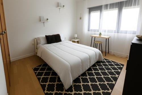 a bedroom with a large white bed and a rug at Freedom Surf House in Serra de El-Rei