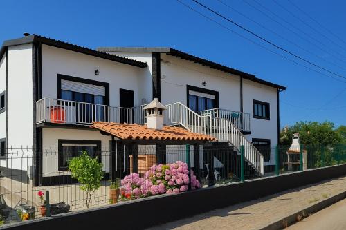 a house with a staircase and flowers in front of it at Freedom Surf House in Serra de El-Rei