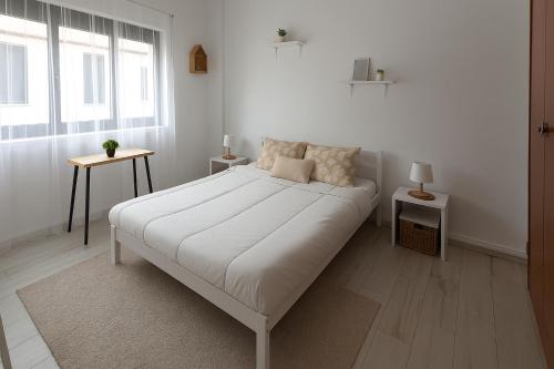 a white bedroom with a bed and a window at Freedom Surf House in Serra de El-Rei