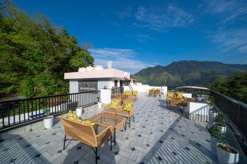 a patio with chairs and tables on a balcony at Perfectstayz Premium Mystic falls with Rooftop Pool & Cafe in Narendranagar