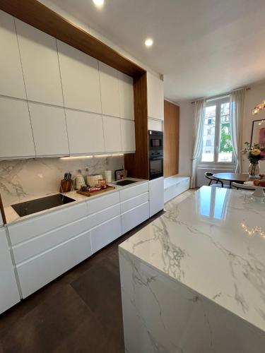 une cuisine avec des armoires blanches et un comptoir dans l'établissement Duplex avec grande terrasse vieux port parking gratuit, à Marseille