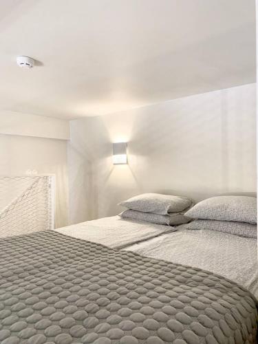 a white bedroom with a large bed with two pillows at Cozy Loft next to Old Town in Tallinn