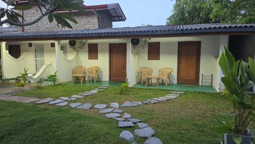 a house with chairs and a garden in front of it at One Decision Hostel in Unawatuna