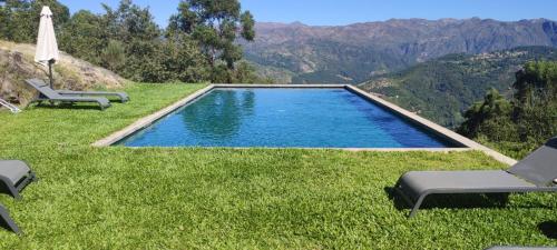 a swimming pool in the grass with chairs and an umbrella at Quinta da Riba Má in Santa Leocádia