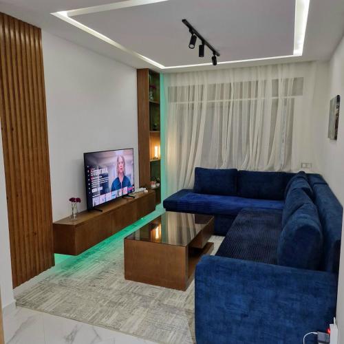 a living room with a blue couch and a tv at Luxury apartment in Martil in Martil