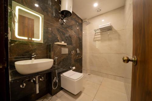 a bathroom with a sink and a toilet and a mirror at Perfectstayz Premium Mystic falls with Rooftop Pool & Cafe in Narendranagar