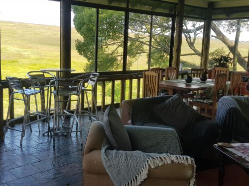 a living room with a couch and tables and chairs at Paradise View Guesthouse in Graskop