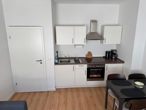 a kitchen with white cabinets and a table and a door at Altstadtinsel am Johanneum 22 in Lübeck