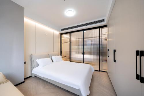 a white bedroom with a large white bed in it at Today Aparthotel West Lujiazui Shanghai in Shanghai