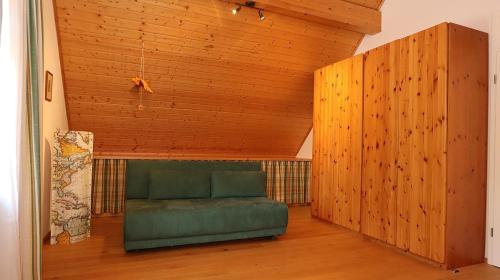 a green couch in a room with a wooden ceiling at Ferienhaus-Winzerhaus Sasbach in Sasbach am Kaiserstuhl