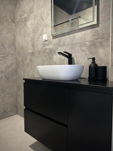 a bathroom with a white sink on a black counter at Premium Line Apartman 3 in Sombor