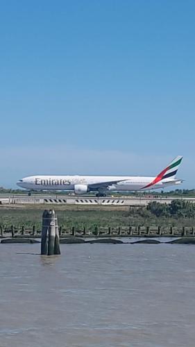 an airplane is sitting on a runway next to water at Fly to Venice Airport View locazione turistica in Venice