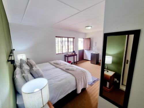 a bedroom with a bed with white sheets and a mirror at Farmlands Guesthouse in George