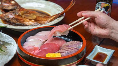 a person holding chopsticks in a bowl of food at 熱海の隠れ里 in Atami