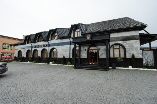 a building on a cobblestone street in front at Готель-ресторан Vertex in Tyachiv