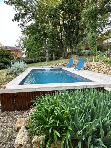 - une piscine avec deux chaises bleues dans la cour dans l'établissement Villa La Sittelle, à Masseboeuf