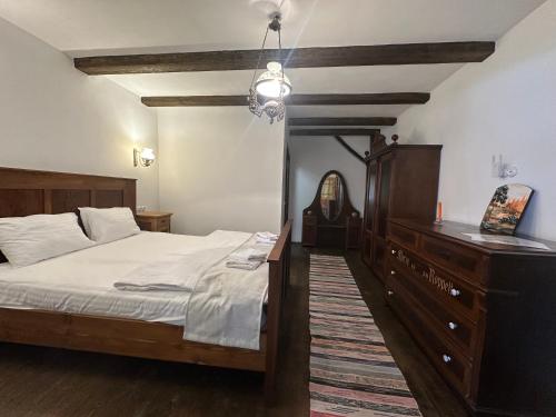 a bedroom with a bed with a dresser and a mirror at Castle View Saschiz - Traditional Guesthouse in Saschiz