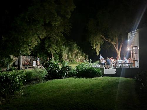 a group of people sitting at a table in a garden at night at Farmlands Guesthouse in George