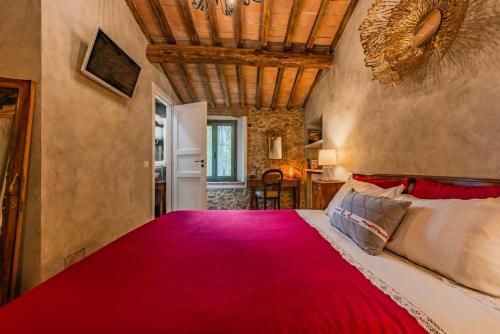 a bedroom with a large bed with a red blanket at B&B Podere Camaiano in Roccastrada