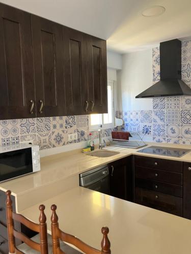una cocina con armarios negros y azulejos azules y blancos en Cullera Marisa, en Cullera