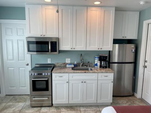 a kitchen with white cabinets and a stainless steel refrigerator at Beachgate Condo Suites and Hotel 232 condo in Port Aransas