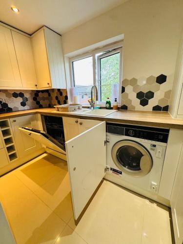 a kitchen with a washing machine and a sink at Swanky3Bed HomeModern Kitchen in Dudley