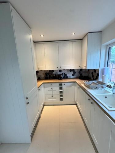 a white kitchen with white cabinets and a sink at Swanky3Bed HomeModern Kitchen in Dudley