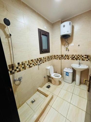 a bathroom with a toilet and a sink at شاليه عائلي في قرية جراند هيلز طابق أرضي بحديقة خاصة غرفتين نوم وريسبشن واسع in Dawwār ‘Abd Allāh