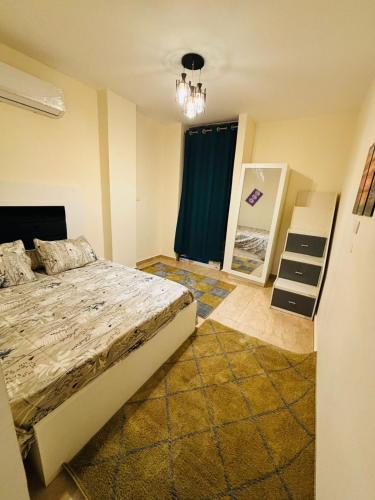 a bedroom with a bed and a mirror at شاليه عائلي في قرية جراند هيلز طابق أرضي بحديقة خاصة غرفتين نوم وريسبشن واسع in Dawwār ‘Abd Allāh