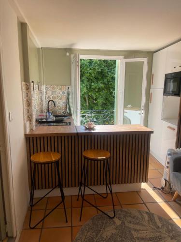 une cuisine avec deux tabourets et un comptoir avec une fenêtre dans l'établissement Angel azur, à Nice
