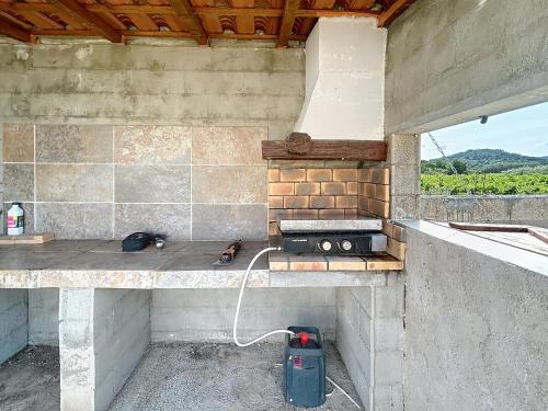 an outdoor kitchen with a stove and a counter top at Villa Grivia - Maison avec grand jardin - Piscine - Pétanque - Ping Pong in Saint-André-de-Roquelongue