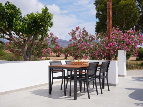 a wooden table and chairs on a patio with pink flowers at The Mill in Karpathos Town