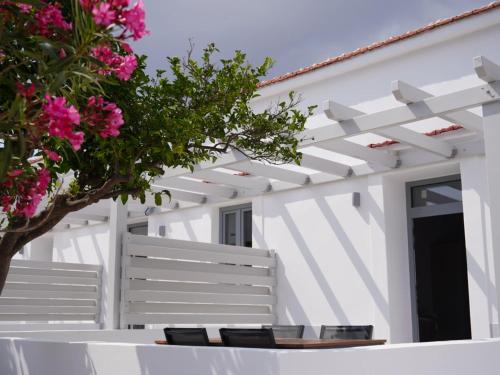 a white house with a white fence and pink flowers at The Mill in Karpathos Town