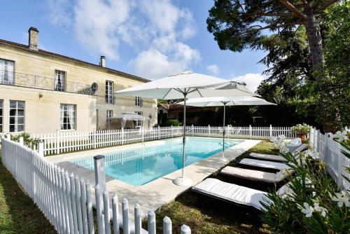 - une piscine avec 2 chaises longues et un parasol dans l'établissement Belle demeure XIXè au coeur des vignes, à Cambes