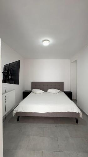 a white bedroom with a bed and a flat screen tv at Luxury Apartment 2BR & Jacuzzi Near Expo 12 & ING Arena in Brussels