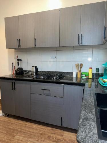 a kitchen with white cabinets and a black counter top at Zaya Residency in Kampala