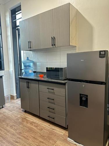 a kitchen with a stainless steel refrigerator and cabinets at Zaya Residency in Kampala