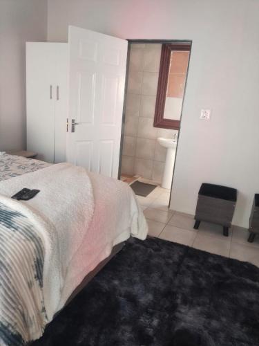 a bedroom with a bed and a bathroom at Rasesa Guesthouse Block V in Soshanguve