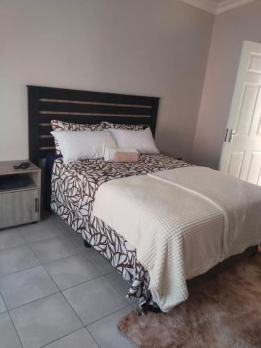a bedroom with a large bed with a black headboard at Rasesa Guesthouse Block V in Soshanguve