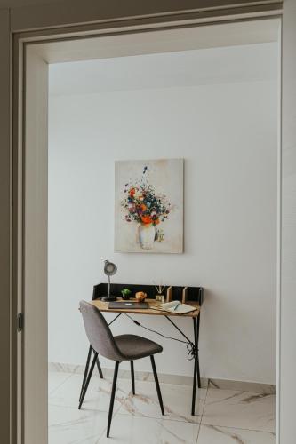 a table and chair in a room with a painting on the wall at Luma apartment - Sliema with Outdoor Space and BBQ Area in Sliema