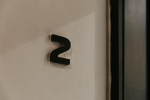 a black door number on a white wall at Luma apartment - Sliema with Outdoor Space and BBQ Area in Sliema